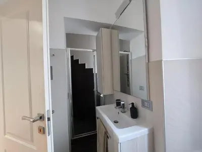 a white bathroom with a sink and a mirror at Nel cuore del Vaticano spazioso ed elegante in Rome