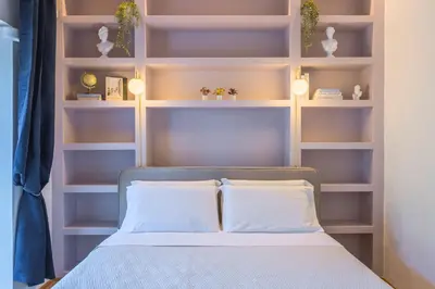 a bedroom with a bed with white pillows and shelves at Vittoria Urban Chic - elegant apartment in the heart of Rome in Rome
