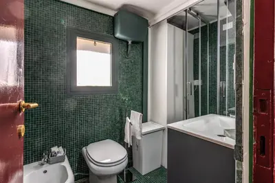 a green tiled bathroom with a toilet and a sink at Domus in Via Del Corso in Rome