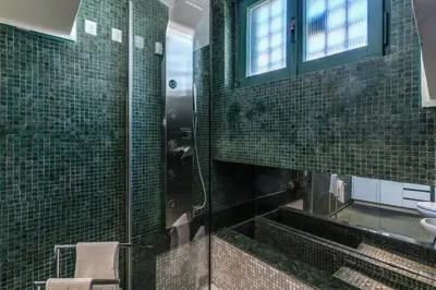 a bathroom with green tiled walls and a sink at Domus in Via Del Corso in Rome