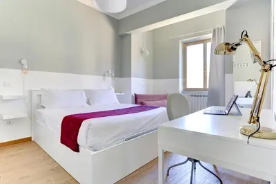 a white bedroom with a bed and a desk at Furio Camillo Studio - Metro A - Netflix in Rome