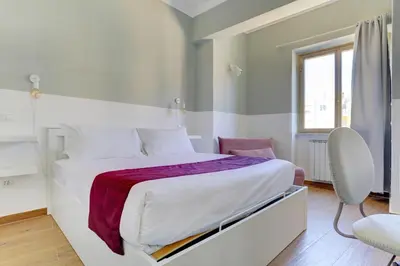 a white bedroom with a bed and a chair at Furio Camillo Studio - Metro A - Netflix in Rome
