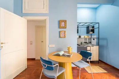 a dining room with a yellow table and blue chairs at Casa Tudor, Charmy Eccentric Flat in Piccola Londra 10 Min from City Center in Rome