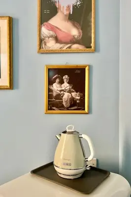 a tea kettle sitting on a table in front of paintings at Casa Tudor, Charmy Eccentric Flat in Piccola Londra 10 Min from City Center in Rome