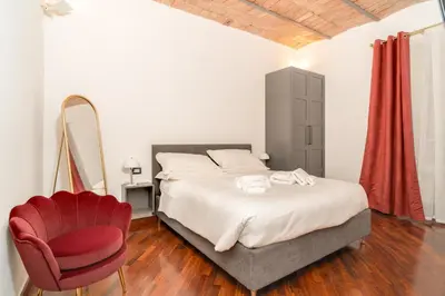 a bedroom with a bed and a red chair at OLEUM Roma Veneto in Rome