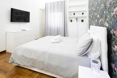 a white bedroom with a white bed with a teddy bear on it at La Casa Di Alice in Rome