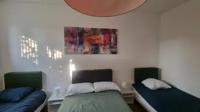 a bedroom with two beds and a painting on the wall at BAM BAM TIBURTINA Guesthouse in Rome