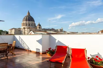 a balcony with two red chairs and a building at Saint Peter's Luxury Terrace Suites in Rome