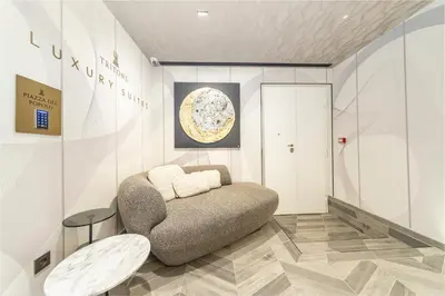 a living room with a chair and a table at Tritone Luxury Suites Piazza del Popolo in Rome
