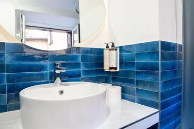 a blue tiled bathroom with a sink and a mirror at Costaguti Holiday Apartment in Rome