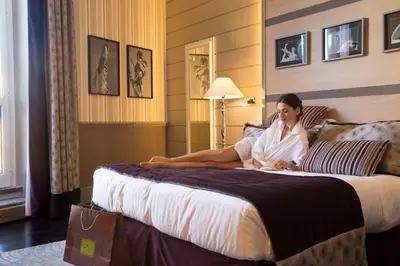 a woman sitting on a bed in a hotel room at The Inn at the Spanish Steps Luxury Collection - Spanish Step Suites in Rome