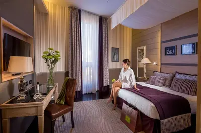 a woman sitting on a bed in a hotel room at The Inn at the Spanish Steps Luxury Collection - Spanish Step Suites in Rome