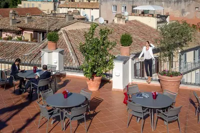 two people are sitting at tables on a balcony at The Inn at the Spanish Steps Luxury Collection - Spanish Step Suites in Rome