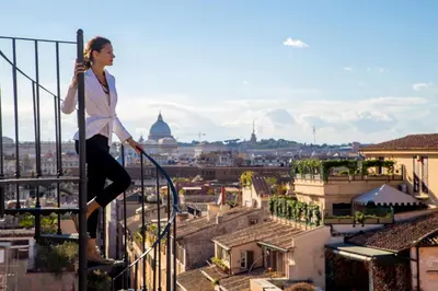 a woman standing on a railing overlooking a city at The Inn at the Spanish Steps Luxury Collection - Spanish Step Suites in Rome
