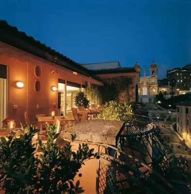 an outdoor patio with tables and chairs at night at The Inn at the Spanish Steps Luxury Collection - The View in Rome