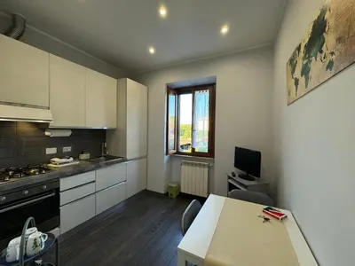 a kitchen with white cabinets and a table with chairs at G&G Apartment in Rome Quadraro in Rome
