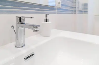 a bathroom sink with two faucets and a roll of toilet paper at When in Rome in Rome