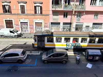 a train traveling down a city street with cars at Pina Charme in Rome