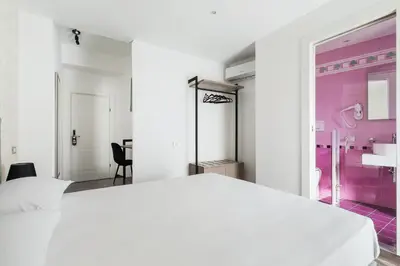 a bedroom with a white bed and a pink bathroom at Adelante Rooms San Giovanni in Rome