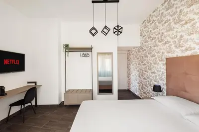 a bedroom with a large white bed and a desk at Adelante Rooms San Giovanni in Rome