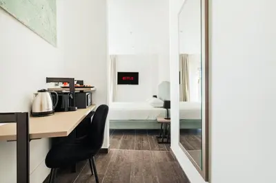 a room with a desk and a bedroom with a bed at Adelante Rooms San Giovanni in Rome