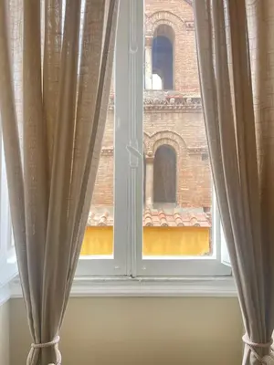 a window with curtains in front of a brick building at Sweet home Trastevere 2- Roma in Rome