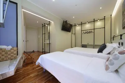 two white beds in a room with a television at San Pietro Luxury Rooms in Rome
