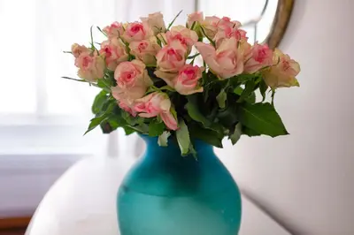 a blue vase filled with pink roses on a table at Interno 16 central and cosy in Rome
