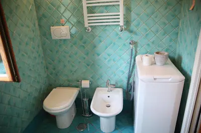 a green tiled bathroom with a toilet and a sink at Casa del Drago in Trastevere in Rome