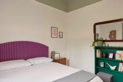 a bedroom with a bed with a purple headboard and a book shelf at Bivio - Casa Verde in Rome