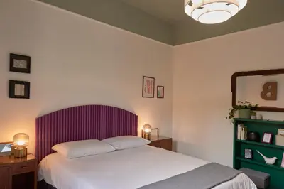 a bedroom with a bed with a purple headboard and a mirror at Bivio - Casa Verde in Rome