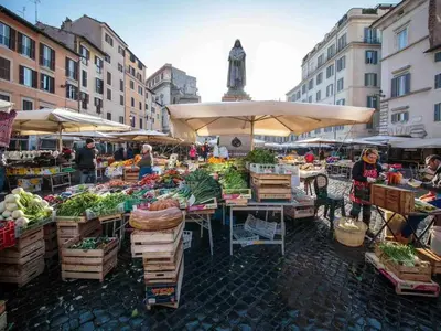 a market with fruits and vegetables on tables with umbrellas at Appartamento familiare nel cuore di Roma in Rome