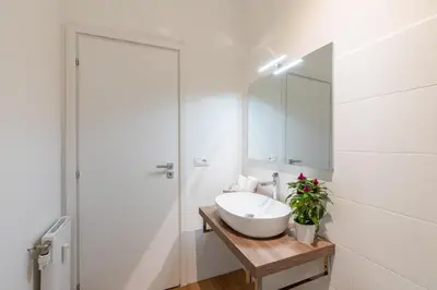 a white bathroom with a sink and a mirror at Vatican Oasis - Free Parking, 4-6 pax, 2 bedrooms in Rome