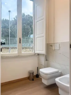a white bathroom with a toilet and a window at Montezebio Boutique Rooms in Rome