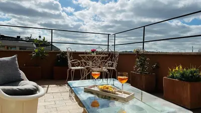 a balcony with a table and two glasses of wine at Terrazza Urania - Penthouse terrace with 360 view of Rome in Rome