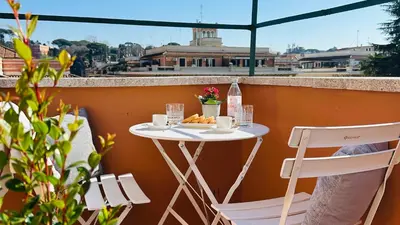 a table and two chairs on a balcony with a table and drinks at Terrazza Urania - Penthouse terrace with 360 view of Rome in Rome