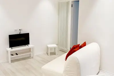 a white living room with a white couch and a tv at CasaFaleria in Rome