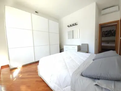 a white bedroom with a large white bed and wooden floors at Like at Home Gianicolense in Rome