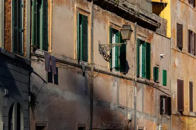 an old building with green shuttered windows on it at The Hive - Holiday Home in Trastevere in Rome