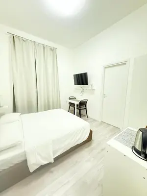 a white bedroom with a bed and a table at The house Of Brindisi in Rome