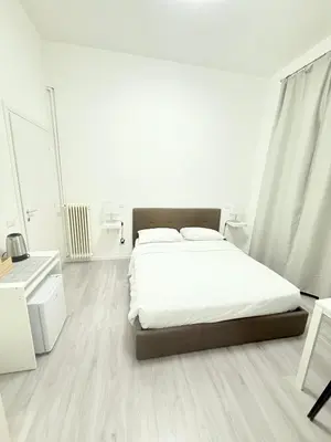 a white bedroom with a bed with white sheets at The house Of Brindisi in Rome