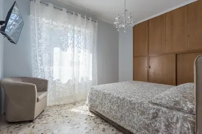 a bedroom with a bed and a chair and a chandelier at Rebecca Apartment in Rome