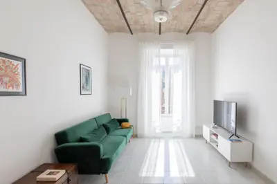 a living room with a green couch and a television at HospitalityRome Sunny San Lorenzo in Rome