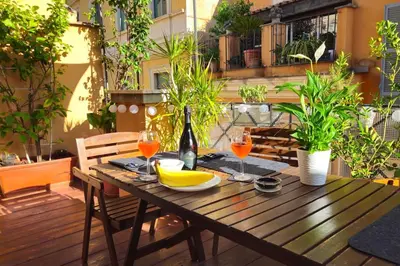 a wooden table with glasses of wine and bananas on a patio at Cozy Modern Apartment with Terrace - Pantheon in Rome