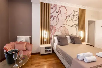 a bedroom with a large bed and a chair at Querini Suite Roma in Rome