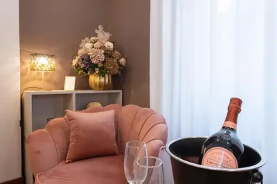 a bottle of wine in a bucket on a chair with glasses at Querini Suite Roma in Rome