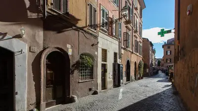 an alley in an old town with buildings and a green cross at Scala Studio by Rental in Rome in Rome
