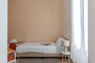 a small white bedroom with a bed and a lamp at Kaizen The Barista 3BR Apartment With Coffee Station in Rome