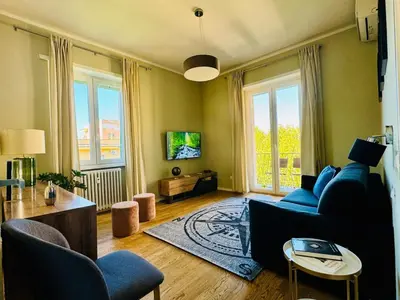 a living room with a blue couch and some windows at The 7th Apartment in Rome