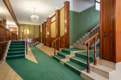 a hallway with green carpet and stairs in a building at La CASA di EMY in Rome